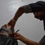 Barbeiro fazendo a barba de um cliente